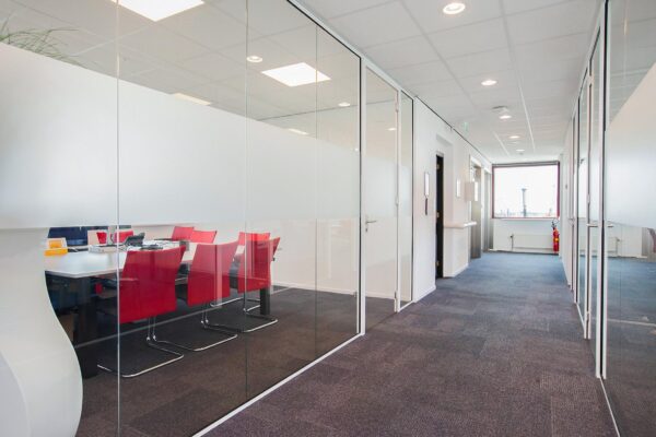 Moderne kantoorruimte aan de Laan der Verenigde Naties met glazen vergaderruimte en rode stoelen.